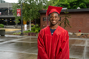 EvCC graduate Aiden Luhr on campus in graduation cap and gown
