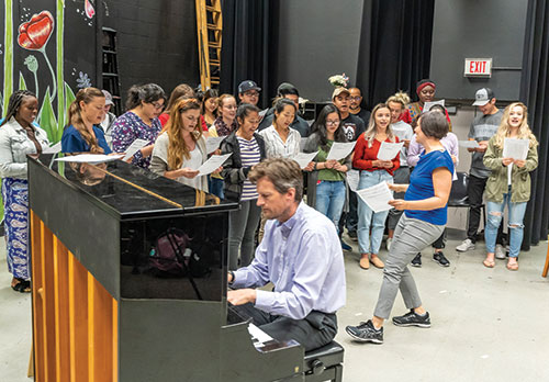EvCC biology instructors Greg Crowther (on piano) and Hilary Kemp lead microbiology students in an extra-credit singalong. Crowther wrote the original song "A Blaze of Glory" to help students understand how the body handles viruses, focusing on the difference between their extracellular stage and their intracellular stage.
