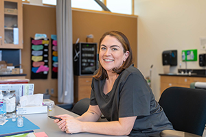 Everett Community College faculty, Amber Samaniego smiles at the camera sitting at a table in a medical lab.