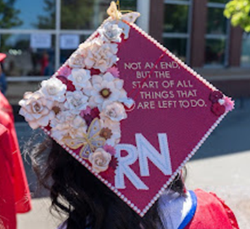 Chloe's graduation cap. It is covered in white flowers and says "Not an end, but the start of all things that are left to do. RN"