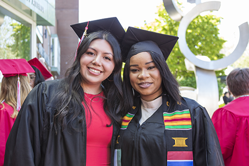 Angela Landeros and Fatou Jaiteh at graduation in graduation regalia. 