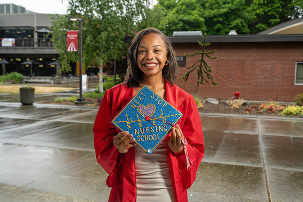 EvCC graduate Jamira Barnes in her graduation cap and gown displaying her decorated cap that shows she will be a future nurse