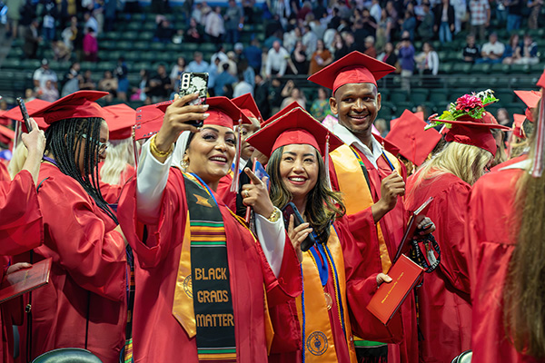 Mailee Nguyen posing with friends for a selfie during EvCC commencement ceremony wearing caps and gowns