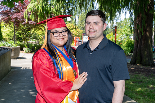 Taliyah in graduation regalia with her husband, Anthony, in front of Jackson Conference Center.