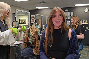 EvCC Cosmetology instructor, Tara Murphy, poses for camera with students working at hair stations in the background.