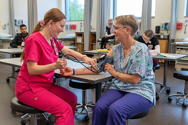 Everett Community College health sciences instructor Beth Adolphsen (right) works with a medical assistant student in a health sciences classroom.