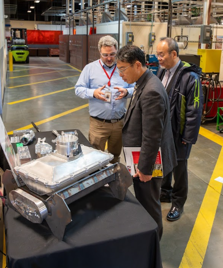 At AMTEC, (from left) EvCC composite instructor Michael Patching shows the components used by EvCC's celebrated machining team to Mr. Takeru Terasawa, from the office of the JFOU President, and JFOU President Hiroaki Hatayama. The machining team earned a national spot in the prestigious Clash of Trades machining reality series finals in 2024.