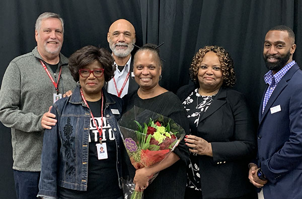 Six people - members of the current and past EvCC board of trustees and EvCC's president, pose for a photo.