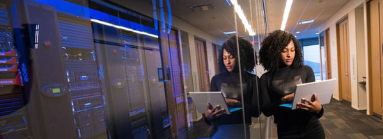 Woman standing next to computer servers.