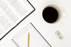 Chris Brunken- photo of a book, a tablet, and a coffee cup on a white ground.