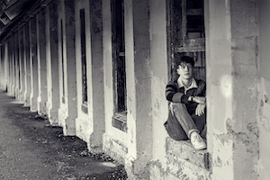 Keegan Baker- black and white photo of a person sitting in a windowsill.