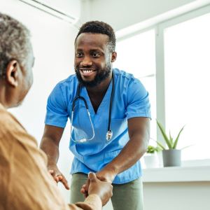 Student in blue scrubs assists a seated male