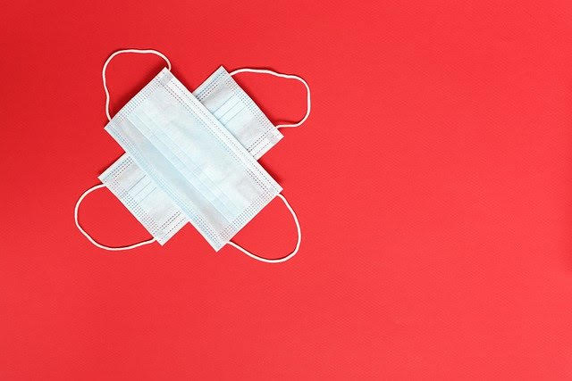 white medical masks make a cross on a red background